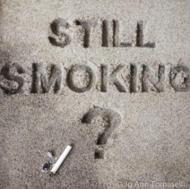 The question 'Still Smoking?' are block printed in sand with a question mark and a cigarette butt nearby.  Best Buy this Image Art  at http://jo-ann-tomaselli.artistwebsites.com/featured/still-smoking-image-art-jo-ann-tomaselli.html