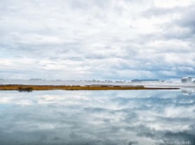 A cloud-filled sky if perfectly reflected in smooth glass-like water