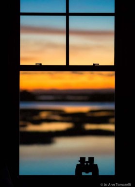 Silhouette of binoculars in window with colorful sky in background