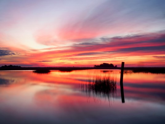 The clouds in the colorful sky at sunrise look like the sails of a boat